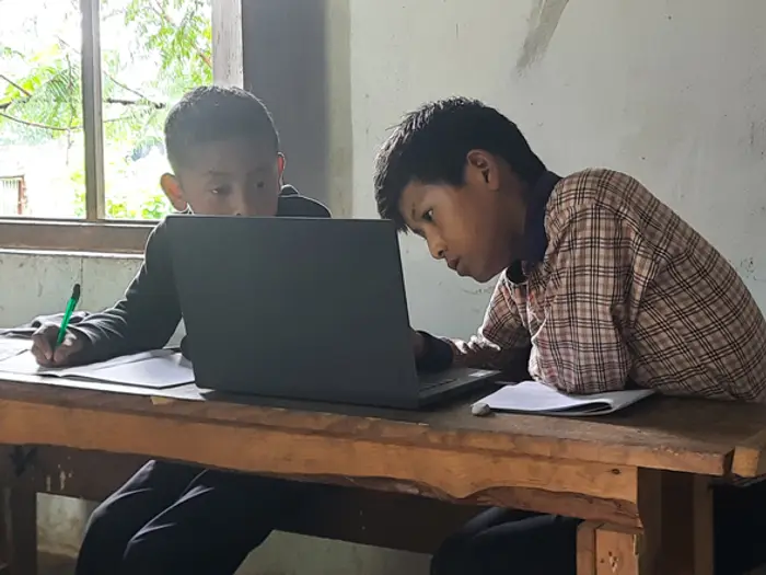 Two older students working on laptops at a desk, Educere Learning Center