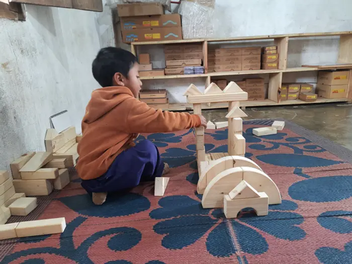 A child building a structure with wooden blocks, Educere Learning Center