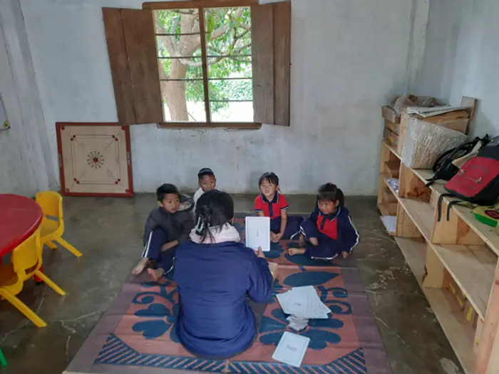 A teacher and small group of children working together on the classroom floor, Educere Learning Center