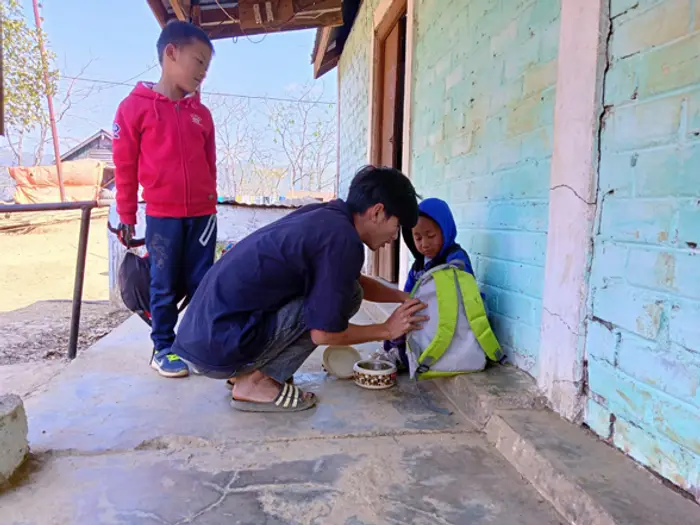 A teacher crouching to help students on the veranda, Educere Learning Center