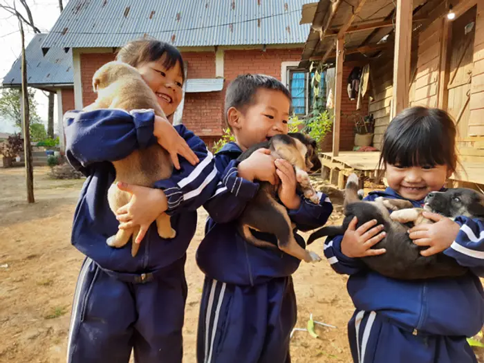 Students in uniform holding puppies outside the classrooms, Educere Learning Center
